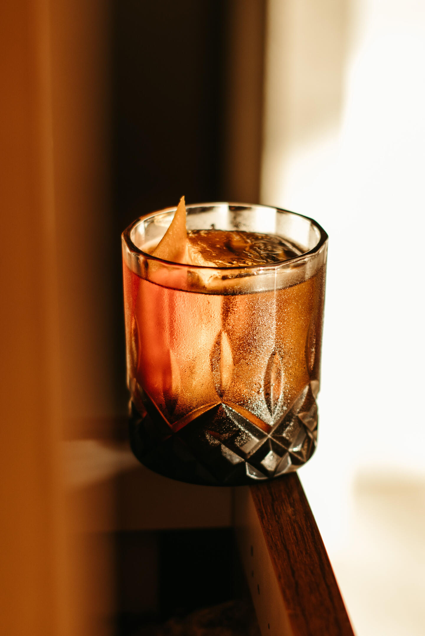 Whiskey cocktail tasting trail tasmania A premium craft whiskey cocktail served in a crystal tumbler with a clear ice block, showcasing local Tasmanian spirits.