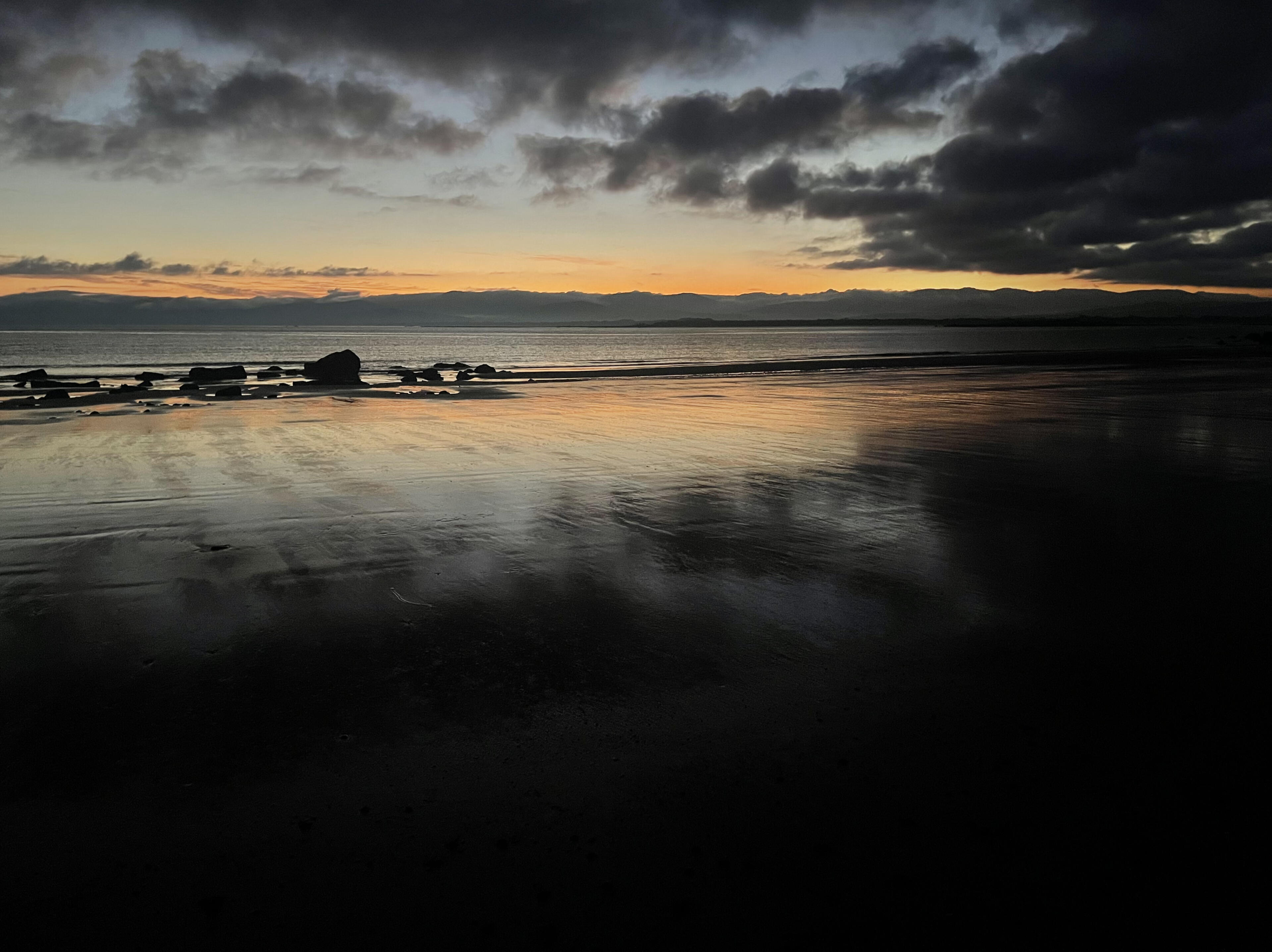 Sunrise at Hawley Beach Golden morning sunlight reflecting across the calm tide and sandy shoreline of Hawley Beach, Tasmania at sunrise.